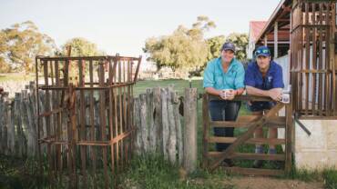 Two farmers leaning on a gate having a coffee break