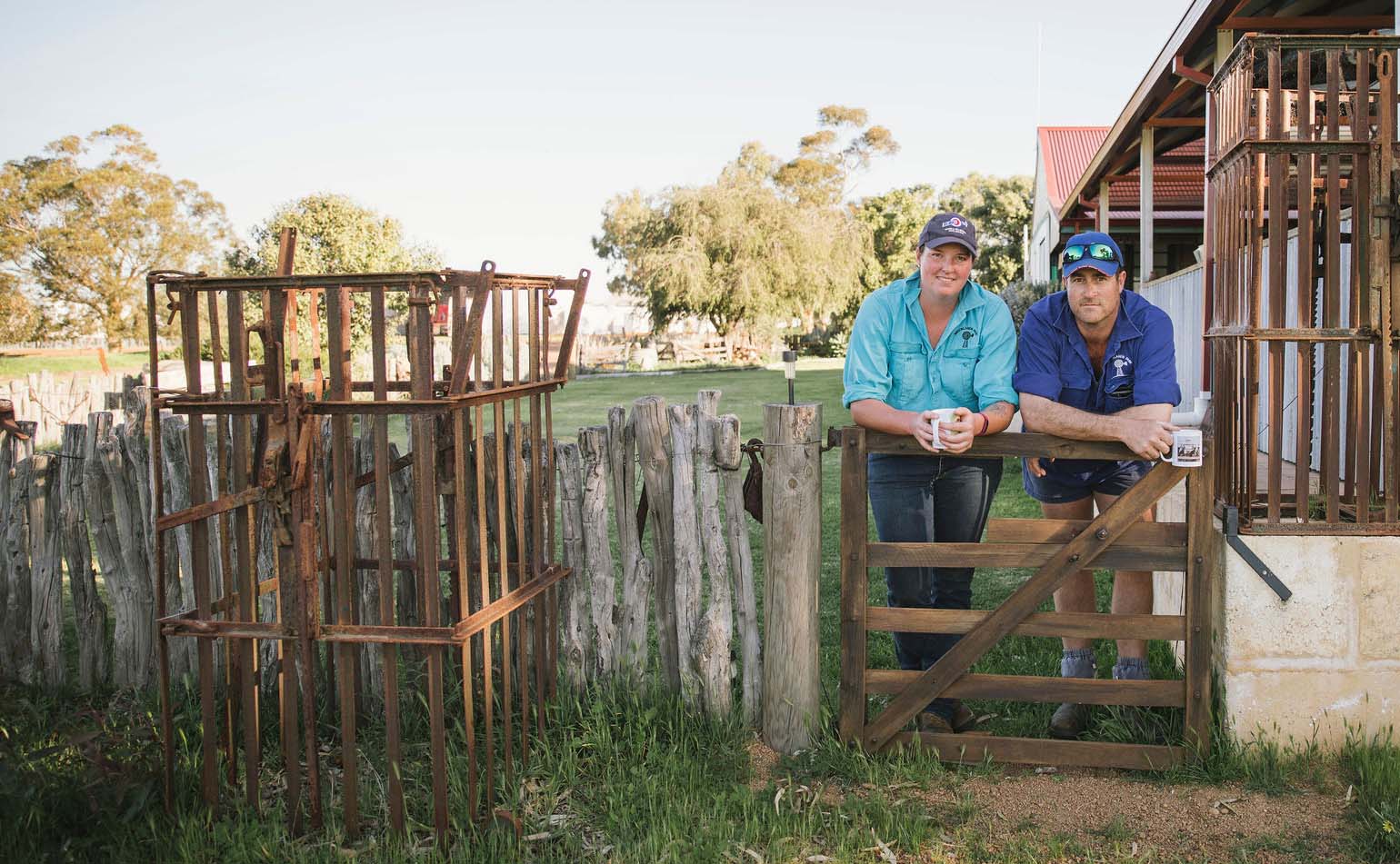 Two farmers leaning on a gate having a coffee break