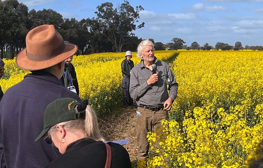 Richard standing in a canola field and presenting at a field trip